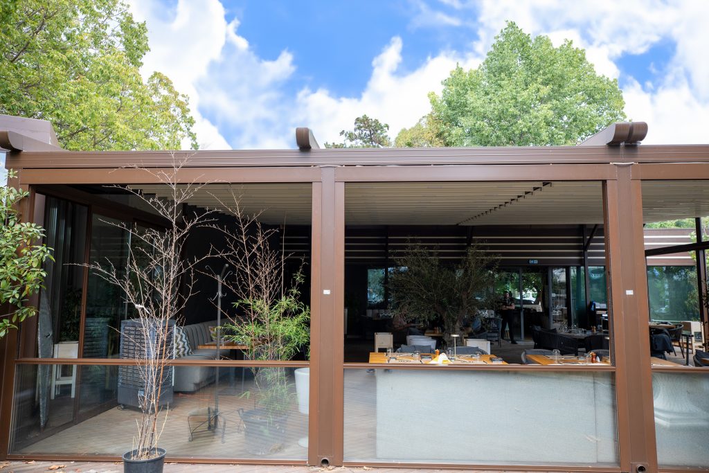 Imaginea surprinde momentul în care luminile moi ale serii sunt reglate cu ușurință pe o terasă acoperită de o pergolă din aluminiu. Confortul personalizat la doar o atingere de distanță.